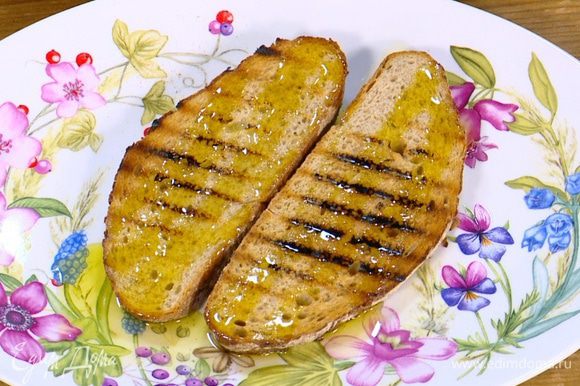 Разогреть сковороду-гриль и подсушить хлеб с двух сторон, затем снять со сковороды и сбрызнуть оливковым маслом.