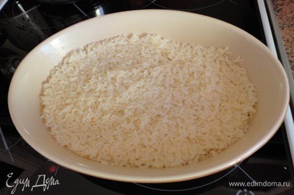 Форму смазать небольшим количеством масла (1 ст.л.), выложить рис и полить его половиной стакана бульона из половины кубика.