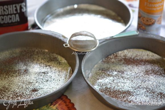 Разогреть духовку до 180°C . Смазать маслом три одинаковые формы 23 см. Вырезать бумагу по форме и выложить на дно каждой формы, посыпать какао-порошком.