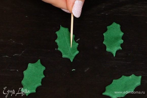 2 вариант — веточки омелы. Из мастики/марципана с помощью формочки вырезаем листики и зубочисткой рисуем прожилки. Если используете мастику, оставьте её немного подсушиться, чтобы листья хорошо держали форму.