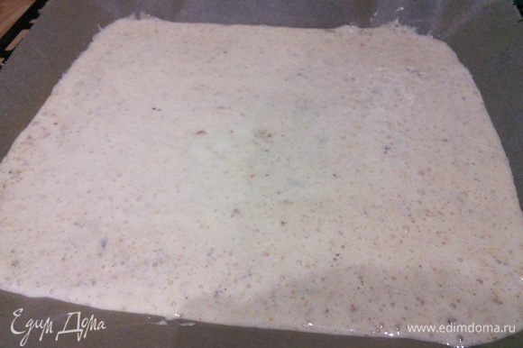Противень выслать пекарской бумагой и распределить бисквитное тесто, разровнять и выпекать в заранее разогретой до 200°С духовке 8 минут.