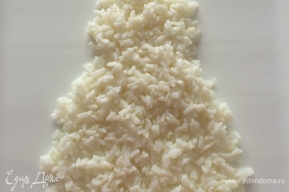 Выкладываем салат слоями в виде Деда Мороза: Первый слой — вареный рис (варим рис в чуть подсоленной воде, затем остужаем), обмазываем майонезом по вкусу.