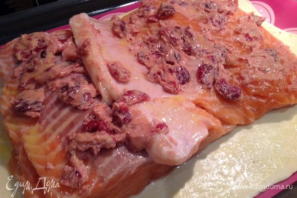 Филе лосося смажьте со всех сторон ароматным маслом с клюквой и выложите на тесто. Смажьте филе и кромку теста взбитым яйцом.