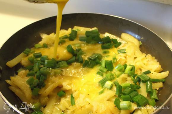 Минуты через две, как отправили белый лучок, посыпаем картофель тертым сыром. Укладываем сверху зеленый лук и заливаем яйцами.