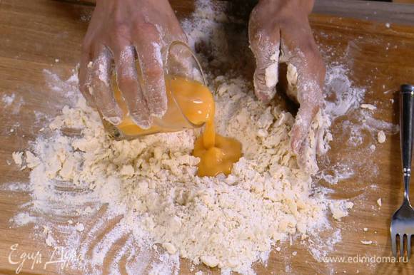 Муку с маслом собрать в холмик, сделать в центре углубление и в несколько приемов влить в него яичную массу, каждый раз перемешивая, затем руками вымесить тесто.