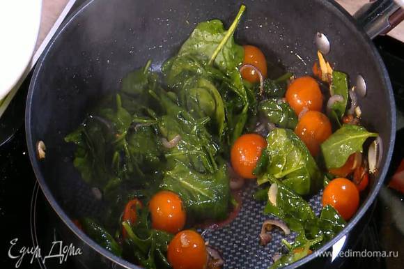 Когда лук и чеснок станут золотистыми, добавить в сковороду чили, помидоры черри и шпинат, перемешать, накрыть крышкой и дать шпинату привять.