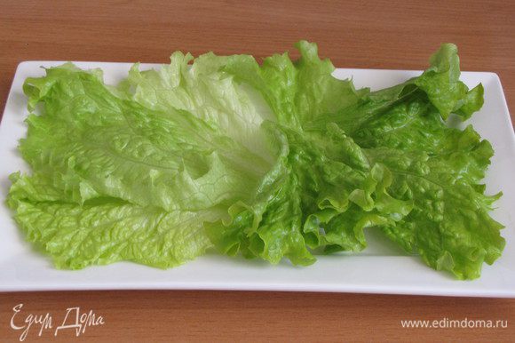 На блюдо или порционную тарелку выложить промытые салатные листья.