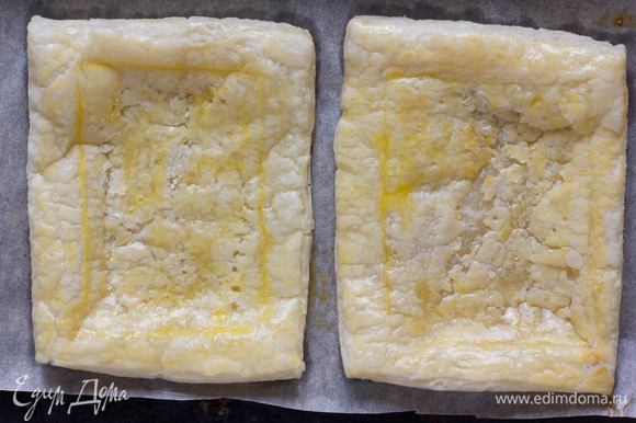 Противень выстелить бумагой для выпечки, выложить тесто, сделать легкий надрез в виде квадрата, смазать поверхность желтком и выпекать в духовке 8–10 минут, до золотистого цвета.