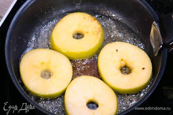 Разогреть в сковороде растительное и сливочное масло, выложить яблочные кружки, посыпать сахаром и обжарить с двух сторон, так чтобы яблоко получилось мягким, но не развалилось, затем переложить в другую посуду.