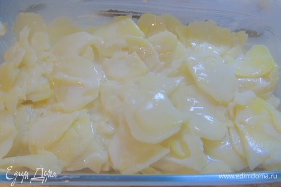 Форму для запекания смазываем сливочным маслом, шумовкой выкладываем половину картофеля.