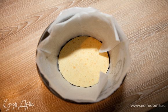 Остывший корж положите в форму. Стенки формы лучше смазать сливочным маслом и обложить слоем пекарской бумаги.