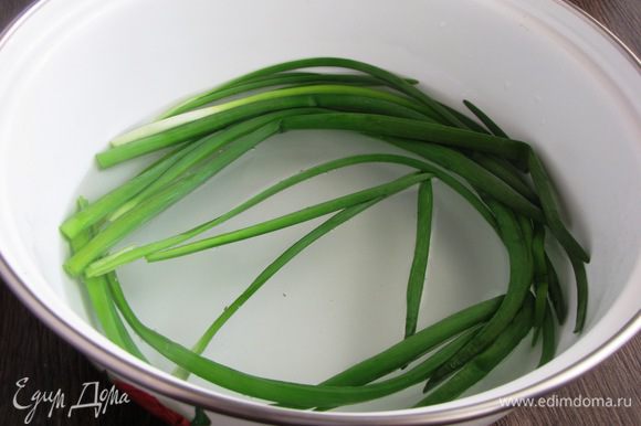 От зеленого лука отрежьте белую часть, выберите хорошие перышки. Положите их в миску и залейте кипятком на несколько секунд. Это нужно для того, чтобы лук не рвался при завязывании.