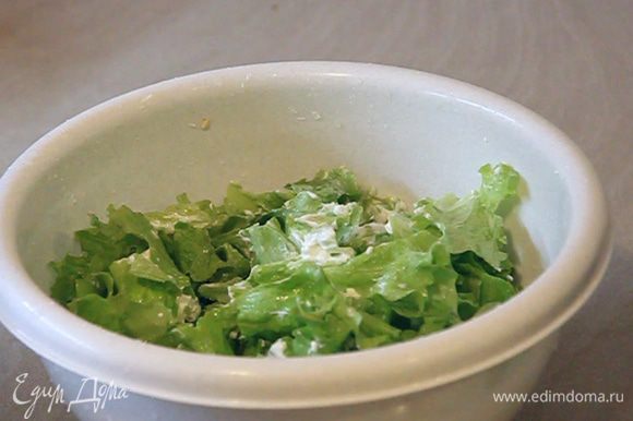 В листья салата добавляем сметану и перемешиваем.