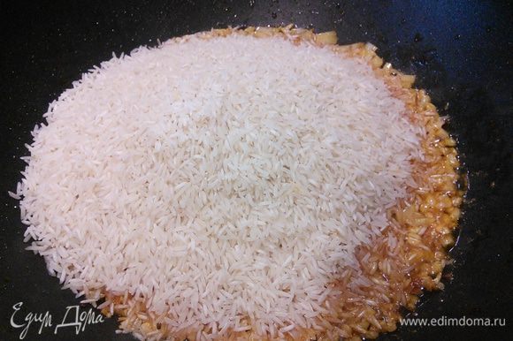 Добавляем рис, перемешиваем, чтобы рис смешался с маслом, обжариваем 1 минуту.