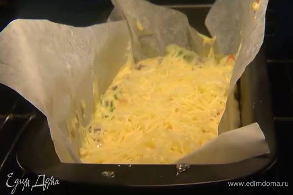 Продолговатую форму выстелить бумагой для выпечки, влить тесто, равномерно распределить и посыпать оставшимся сыром.
