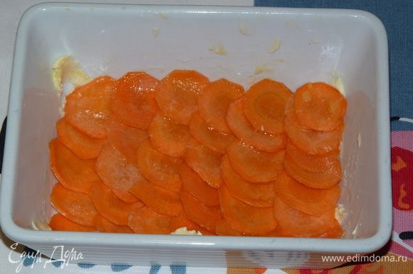 Смазать форму сливочным маслом, выложить внахлест слой морковных кружочков.