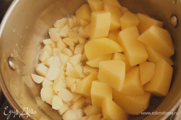 Почистить чеснок и картофель. Чеснок нарезать на 4 части, картофель — крупными кубиками. В кастрюльке разогреть оба вида масла, добавить чеснок и картофель. Тушить около 5 минут, помешивая.