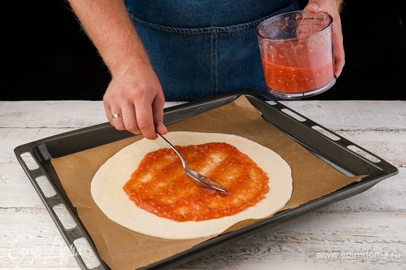 Когда тесто готово, раскатываем его тонким слоем и кладем на противень, покрытый бумагой для выпечки (бумагу для выпечки слегка смазываем оливковым маслом). Смазываем тесто слоем соуса.