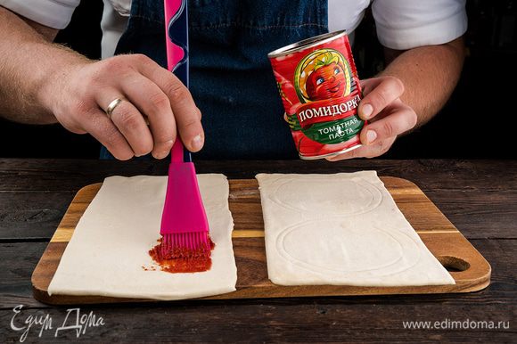 Накрыть противень пергаментом, присыпать его мукой. Из готового теста нарезать квадраты. Смазать их томатной пастой «Помидорка».