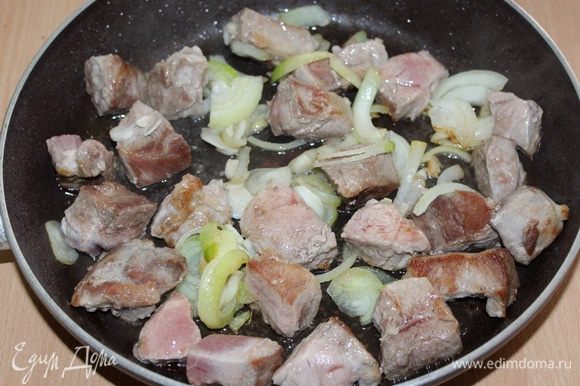 Свинину нарезать небольшими кусочками, обжарить 4 — 5 минуты до золотистой корочки. Добавить нарезанный полукольцами лук и измельченный чеснок, обжариваем.