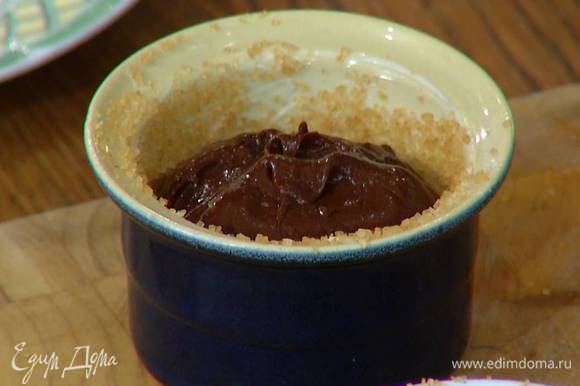 Небольшие керамические формы смазать внутри оставшимся сливочным маслом, посыпать коричневым сахаром и разложить шоколадную массу, заполняя их на 2/3 объема.