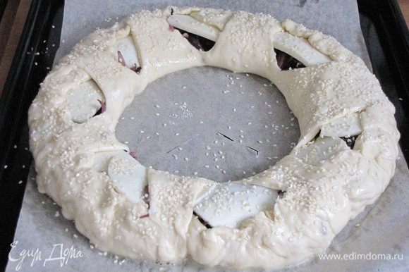 Подвернуть края пирога и накрыть их треугольниками из центра. Смазать пирог слегка взбитым яйцом и посыпать по желанию кунжутом. Поставить в разогретую до 180°С духовку и выпекать минут 30 или до зарумянивания.