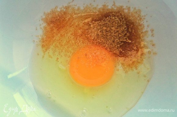 В небольшую миску вбить яйцо, всыпать коричневый сахар.