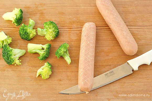 Разделить брокколи на части. С помощью ножа сделать неглубокие надрезы в сосисках в виде ромбиков.