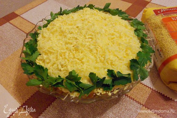 Сверху салат посыпать тертым сыром с раскрошенными желтками и украсить петрушкой.