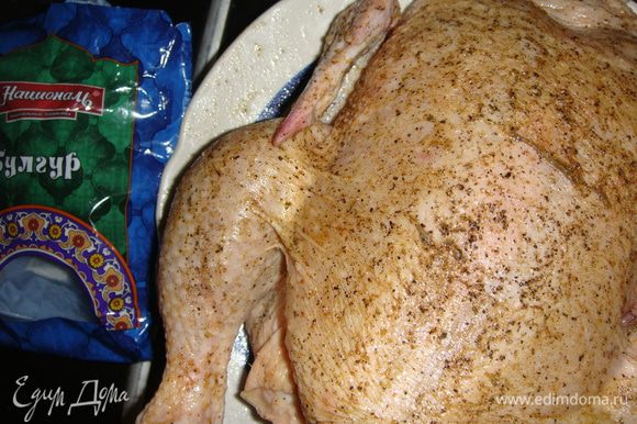 Смазать курицу подсолнечным маслом, натереть солью, приправой для курицы и черным перцем. Чеснок почистить и разрезать пополам. Сделать надрезы в курице и вложить чеснок.