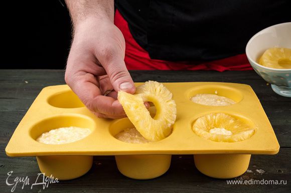 Смазать формочки маслом, наполнить их смесью, украсить кусочками ананаса. Выпекать в духовке 30 минут.