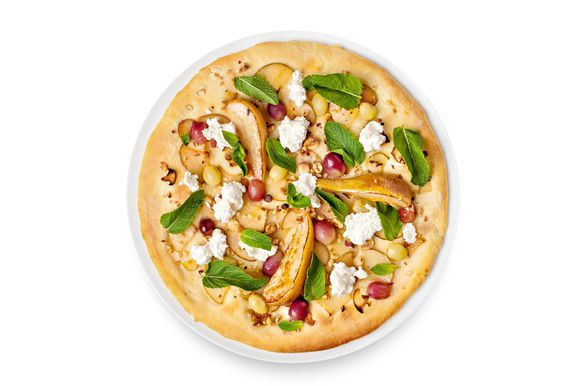На готовую пиццу выложите карамелизованные груши, рикотту и листья мяты.
