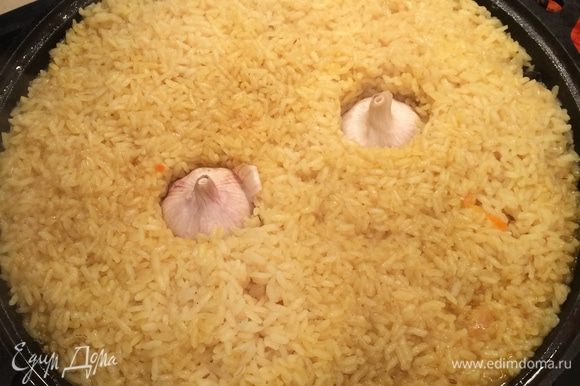 Через 20 минут «утопить» 2 головки чеснока в рис, снова закрыть крышкой и продолжать варить еще 20 минут.
