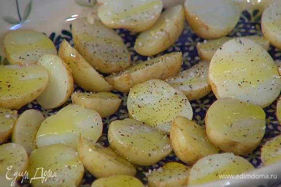 Готовый картофель, не очищая, разрезать пополам (более крупный — на 4 части), выложить в жаропрочную форму разрезами вверх, посолить, поперчить и полить половиной оливкового масла.