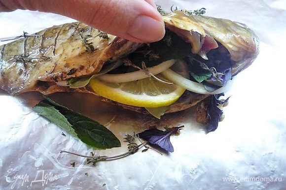 По истечении времени рыбу укладываем на лист фольги, в брюшко кладем дольки лимона, кольца лука, лавровый лист, листики мяты и базилика. Сверху посыпаем солью, перцем и тимьяном.
