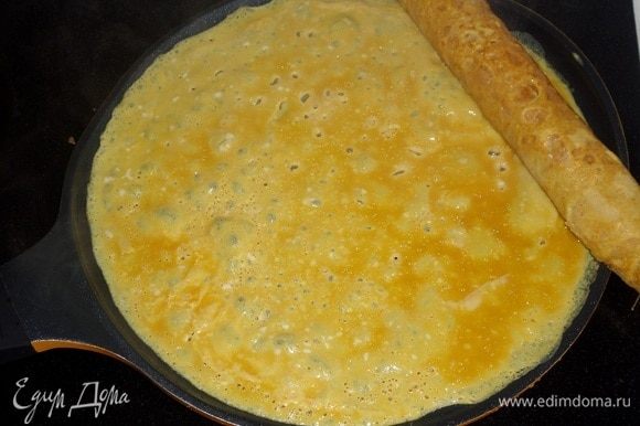 Смазать сковороду маслом и налить очередную порцию яичной смеси. Сразу же положить ранее завернутый рулет.