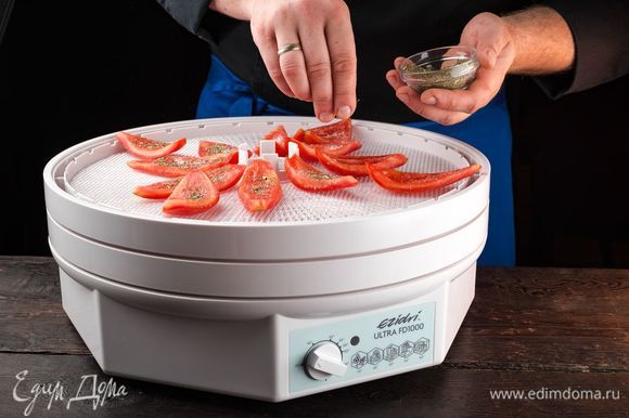 Посолите помидоры и посыпьте сушеными итальянскими травами. Выложите подготовленные помидоры на поддон для сушки срезом вверх. Сушите в течение 6 часов при температуре 70°С.