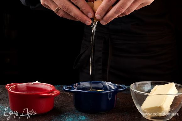 Керамические формочки для выпечки смажьте сливочным маслом, в каждую разбейте по 2 яйца, сохраняя целостность желтка.