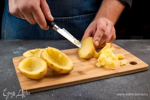 Картофель среднего размера с кожурой хорошо промойте щеткой. Выложите картофель на противень, застеленный пергаментом, сбрызните оливковым маслом и запекайте в разогретой духовке 15 минут. Готовый картофель охладите, разрежьте пополам, выньте часть мякоти, посолите и поперчите. Мякоть картофеля измельчите.