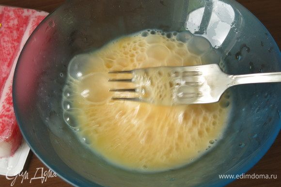 Пока варится рис, приготовим омлет с крабовыми палочками. Сбиваем 2 яйца с щепотками сахара и соли.