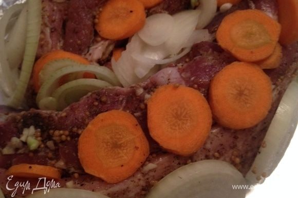 Обложите мясо морковью и луком.