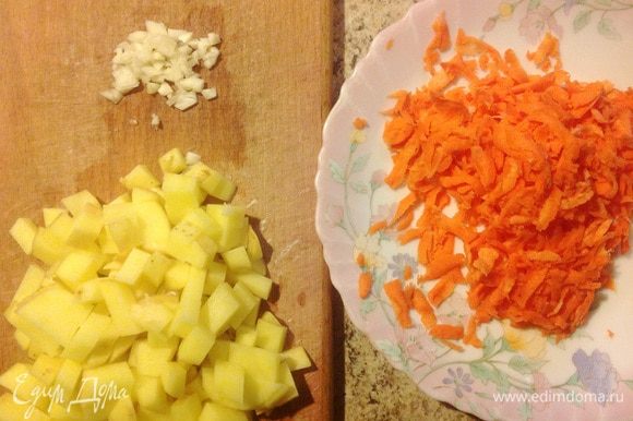 Нарезать картофель кубиками. Мелко порубить чеснок. Морковь натереть на крупной терке.