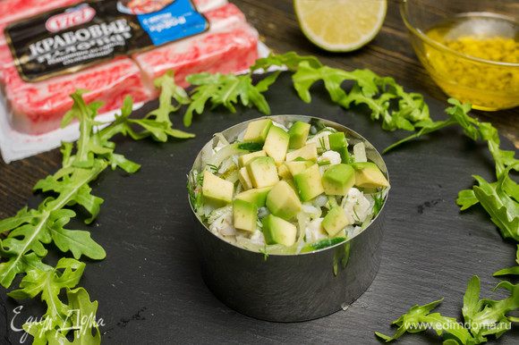 Выкладываем салат в порционную тарелку или форму, а сверху кладем нарезанное кубиками авокадо.