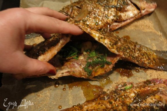 На противень насыпаем сухари панировочные, кладем внутрь каждой рыбы зелень и чеснок.