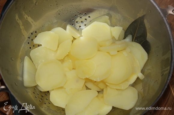 Выложить отваренный картофель в дуршлаг, дать стечь полностью воде, выбросить лавровый лист. Включить духовку, установить термометр на отметку 180°C.