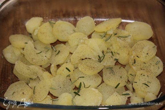 В стеклянную огнеупорную посуду выложить отваренный картофель, распределить по всей поверхности дня посуды. Посыпать молотым черным перцем, измельченными листиками свежего розмарина.