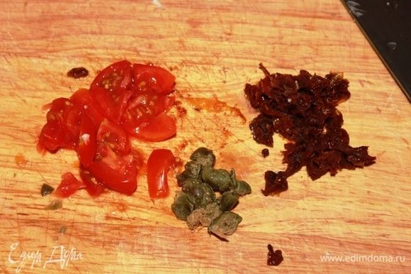 Тем временем нарезать 2 помидора черри, измельчить каперсы (если они у вас хранятся под солью, промойте их немного под проточной водой, чтобы не переборщить с солью), нарезать 1 вяленый томат.