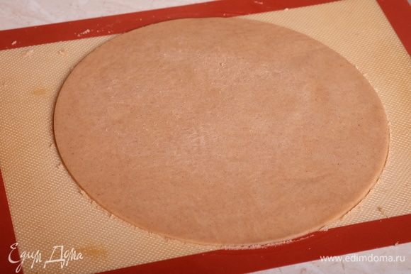 Выпечем коржи из песочного теста. Охлажденное тесто разделить пополам. Раскатать первую часть теста на силиконовом коврике до толщины 3–5 мм. Раскатывать нужно через лист пергамента — так тесто не будет приставать к скалке. Вырезать вырубкой, равной диаметру торта (26 см), круг. Охладить его прямо на коврике в холодильнике минимум 2 часа. Остатки теста сохранить.