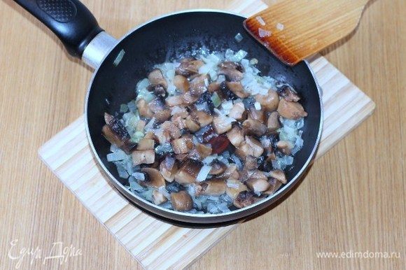 Добавляем порезанные дольками шампиньоны, сливочное масло, солим, перчим и жарим до готовности грибов.