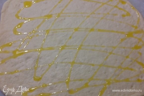 Берем одну часть и раскатываем его в пласт, вторую пока отправляем обратно в миску под полотенце, чтобы оно не обветривалось. Поверх пласта поливаем оливковым маслом.